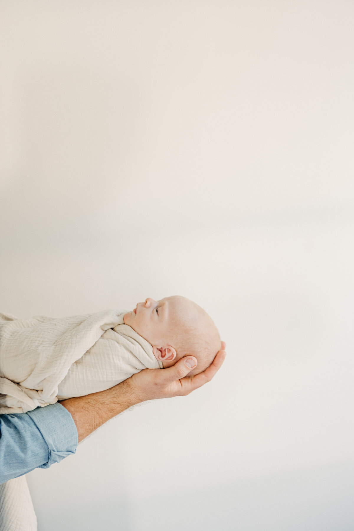 Dad cradles baby's head in his palm.