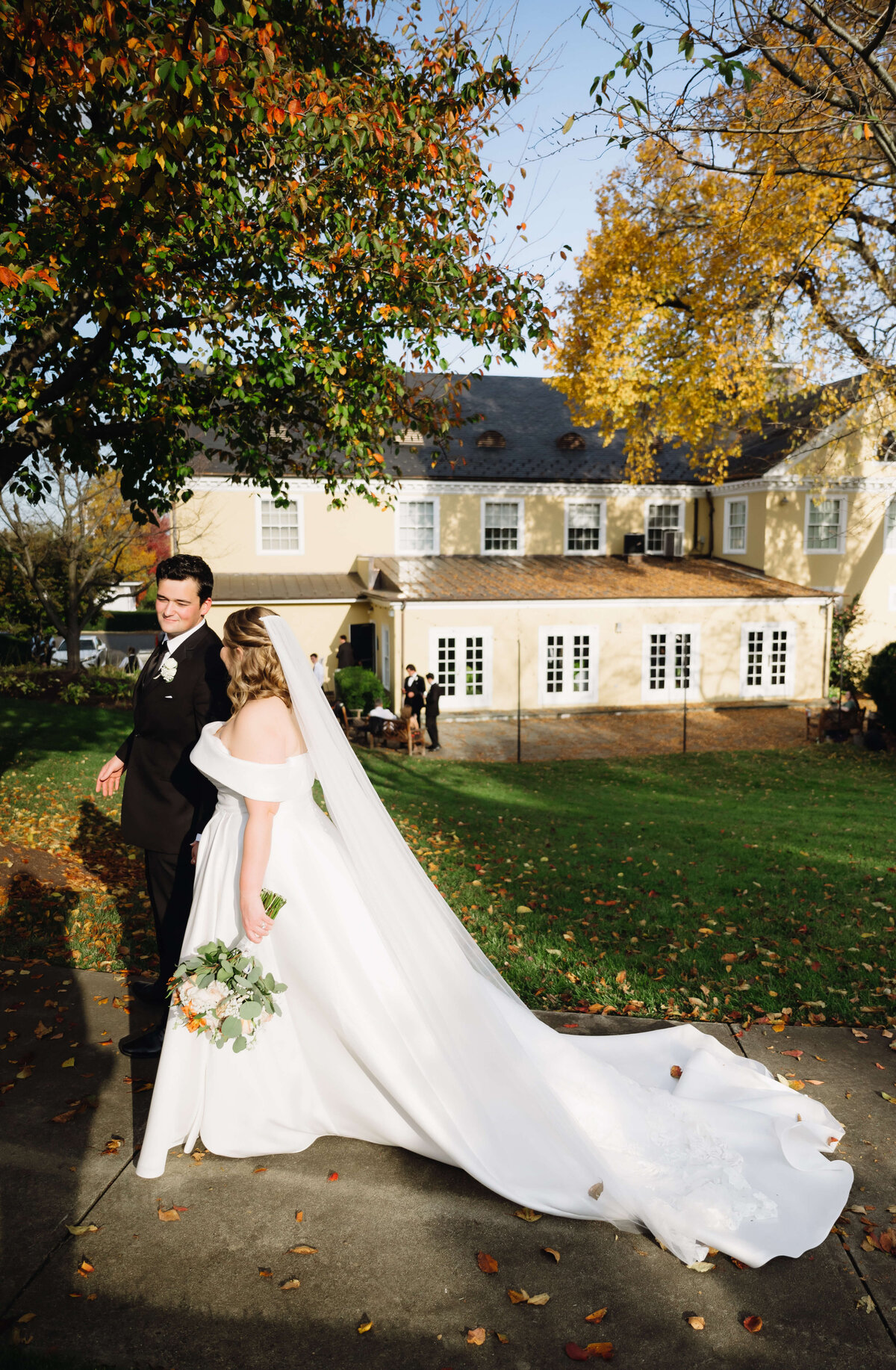 bride and groom holding hands at sunset and walking through a lawn together for their fall wedding at Richmond wedding venues back patio space