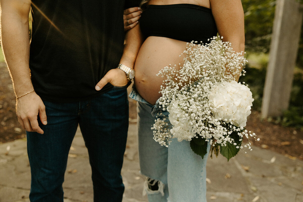 couple posing with flowers during their maternity session at The Mill At Fine Creek with Powhatan Maternity Photographer, Three Bridge Photography