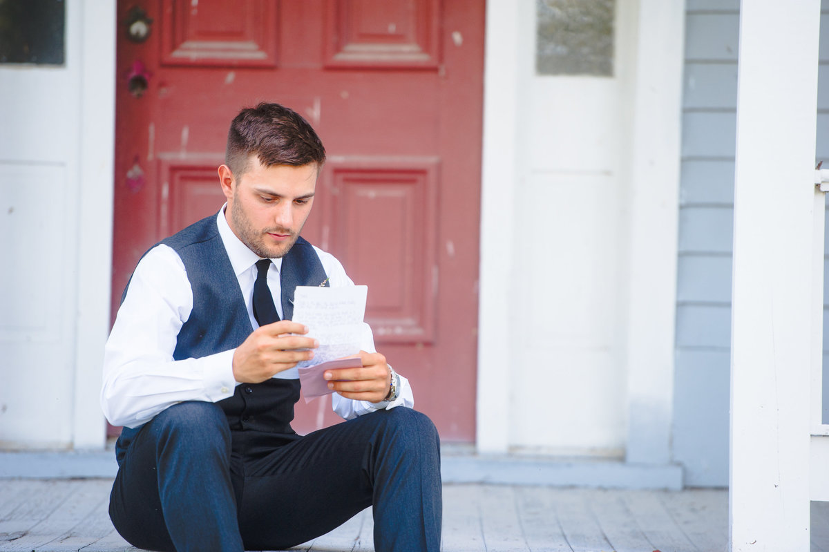 Groom reads a letter from his bride on their wedding day at Chandler Hill Vineyard in Missouri.