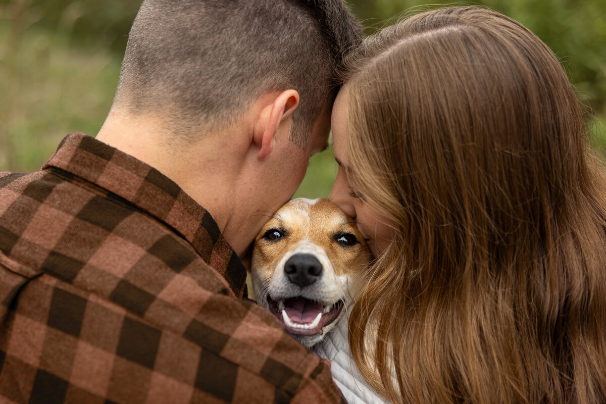 man and woman kissing a dog's head