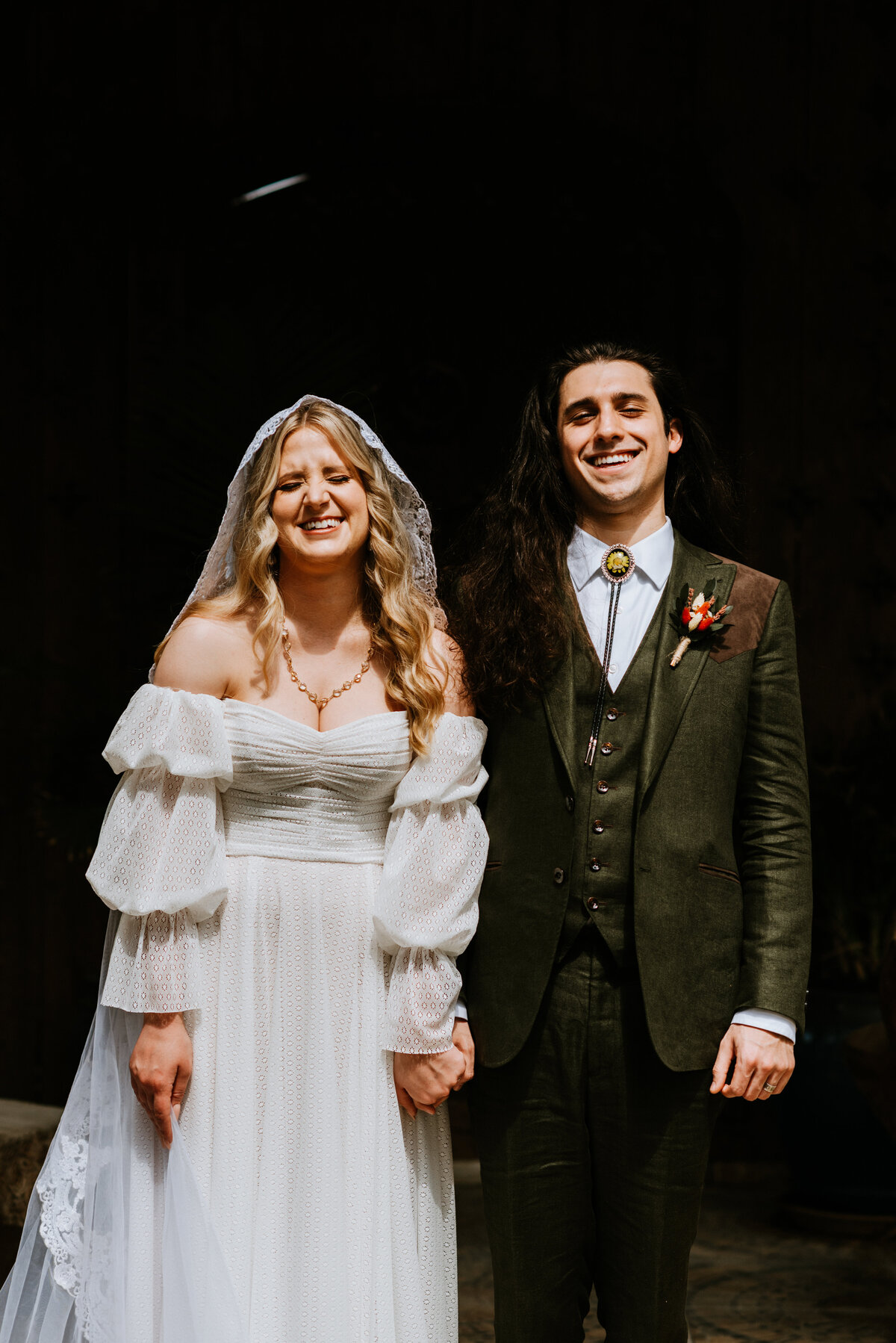 bride and groom laughing towards camera in harsh light