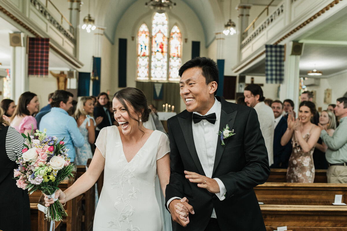 Excited newlyweds wave to guests as their leave their wedding ceremony