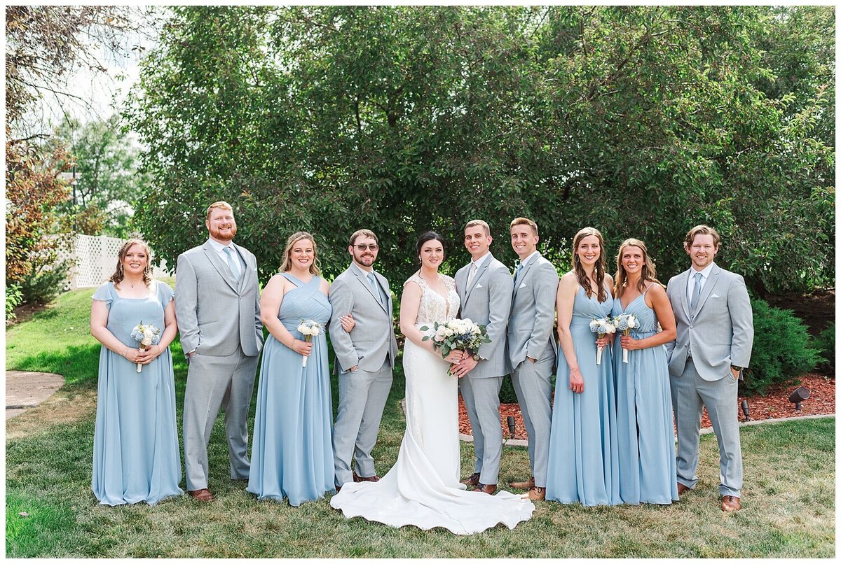 Denver wedding photographer captured a photo of the wedding party and bride and groom at Chateaux at Fox meadows venue with bridesmaids in blue dresses and men in grey suits