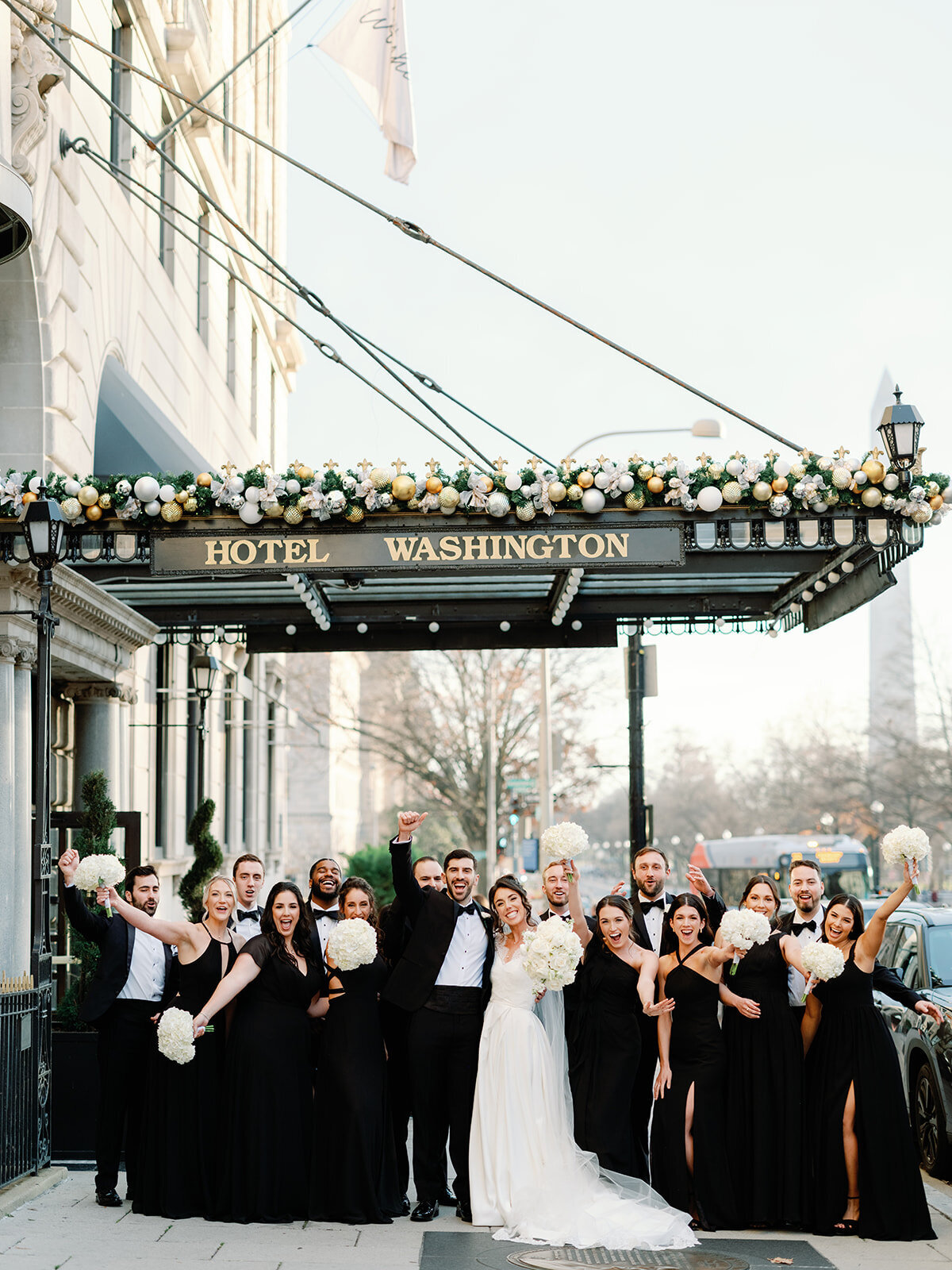 Bridal party cheers in front of Hotel Washington with Bride and Groom 