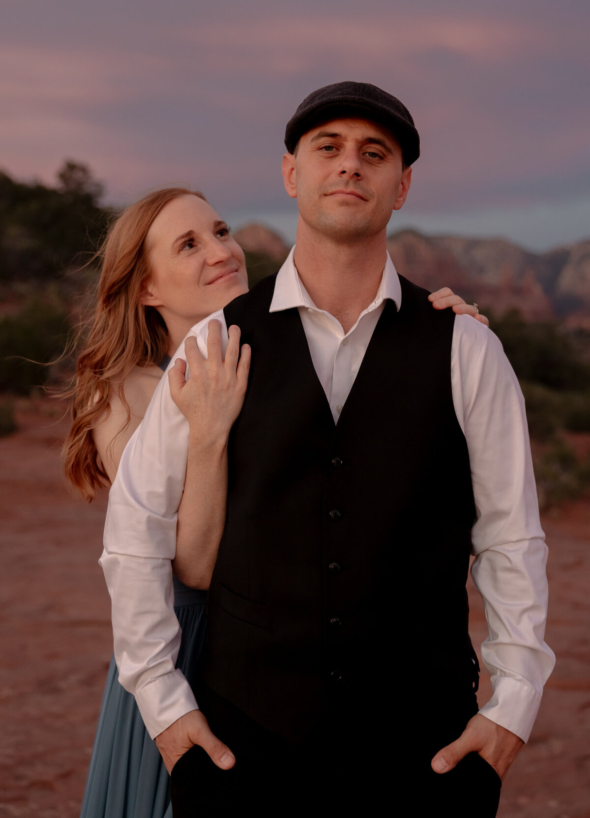 Couple standing against red rock backdrop during Sedona engagement session