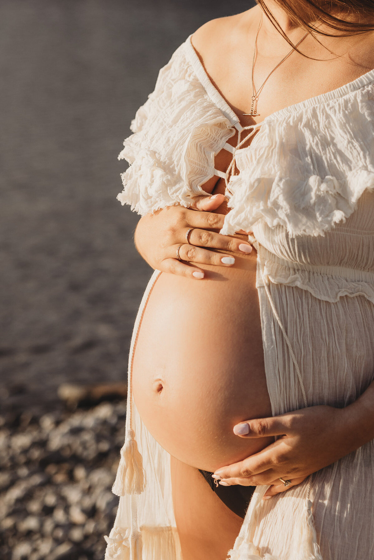pregnant woman standing with hand on belly in wanaka during her maternity session