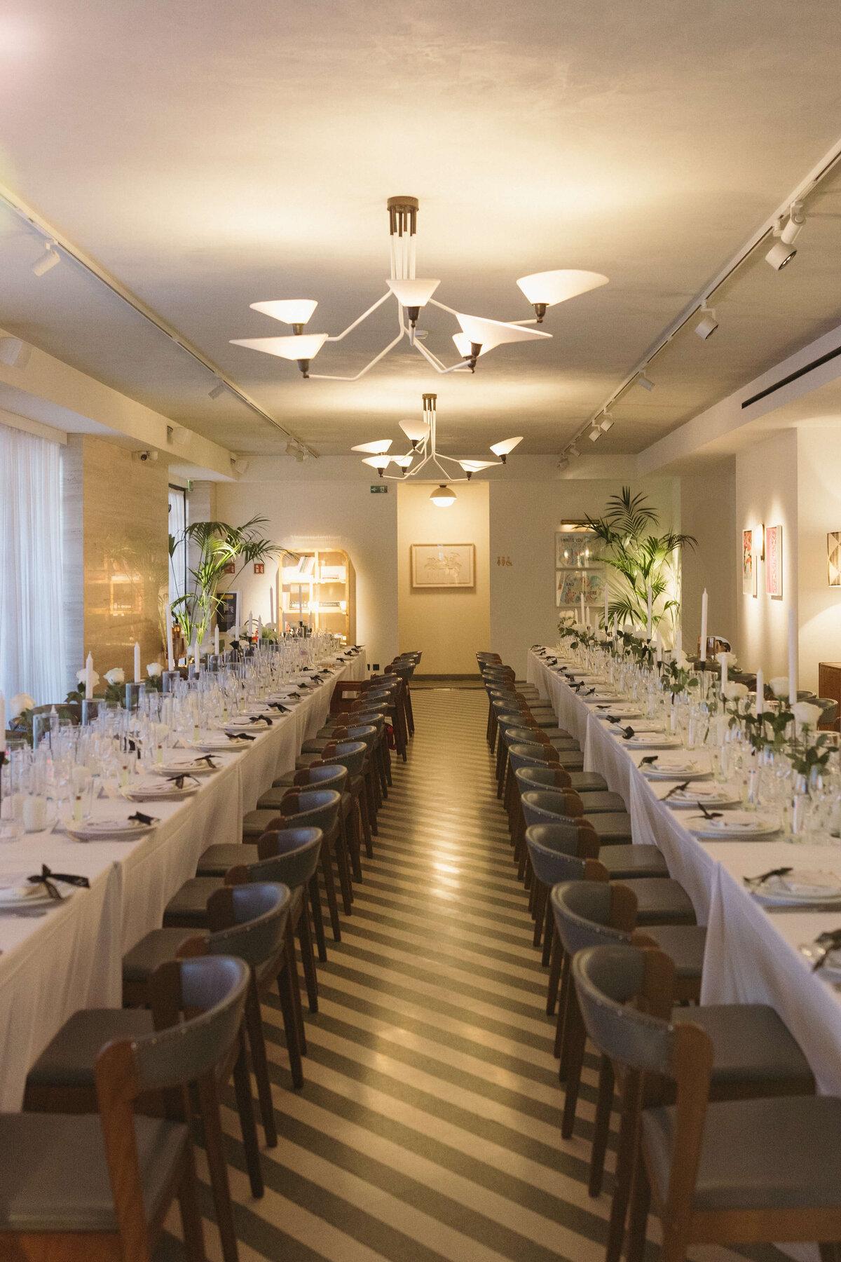 Minimalist candlelit wedding table setup with white florals and modern chairs

