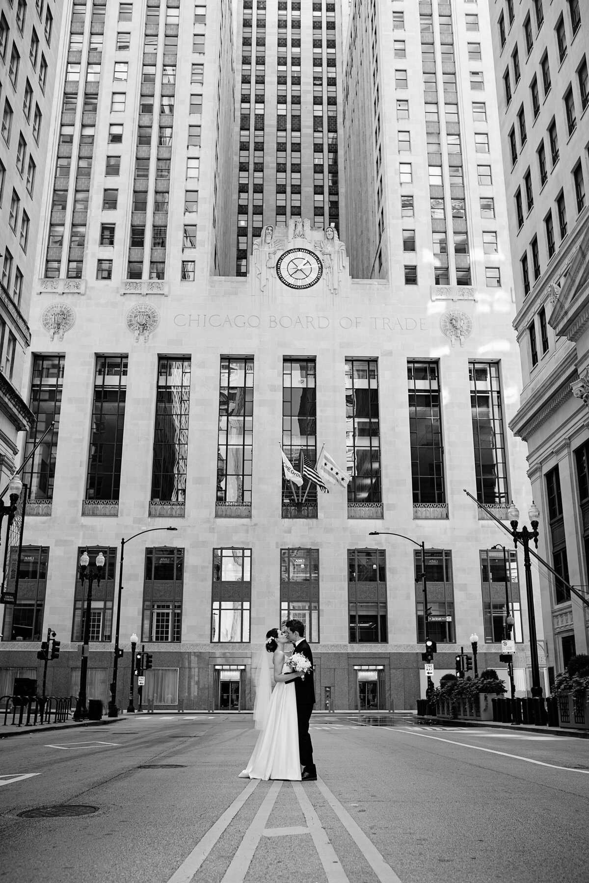 Black and white picture of Newlyweds kissing  in front of Chicago board of trade building