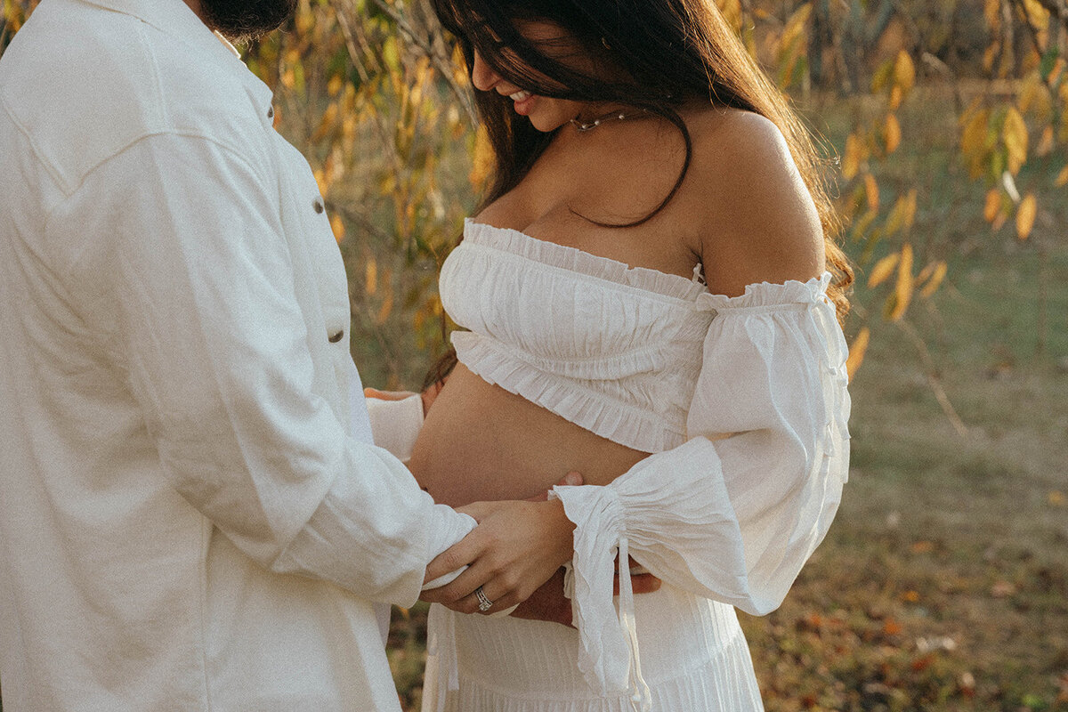 man holds woman's pregnant belly during maternity photoshoot captured by NYC maternity photographer Elsie Goodman