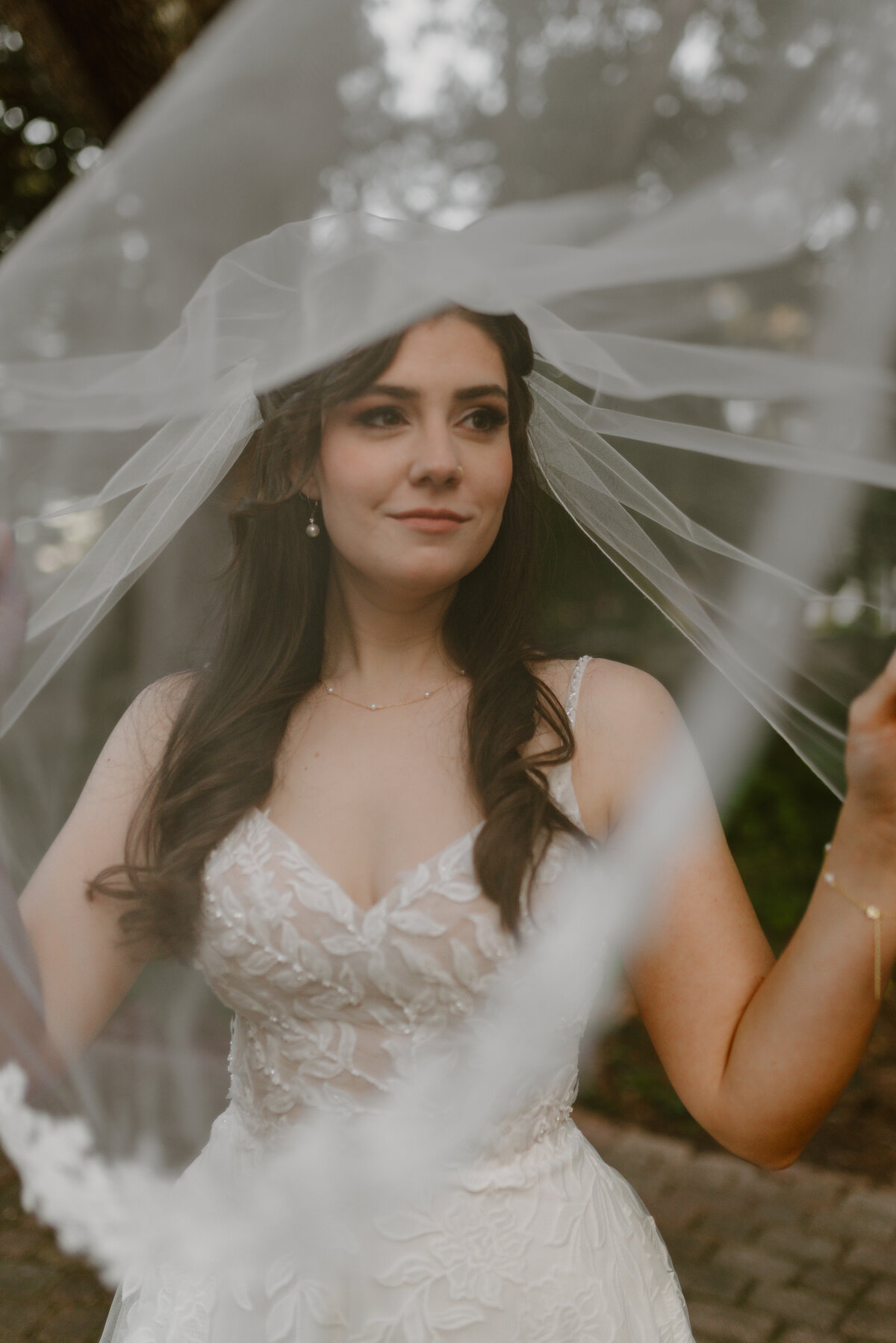 a portrait of a bride underneath her veil thats flowing in the wind.