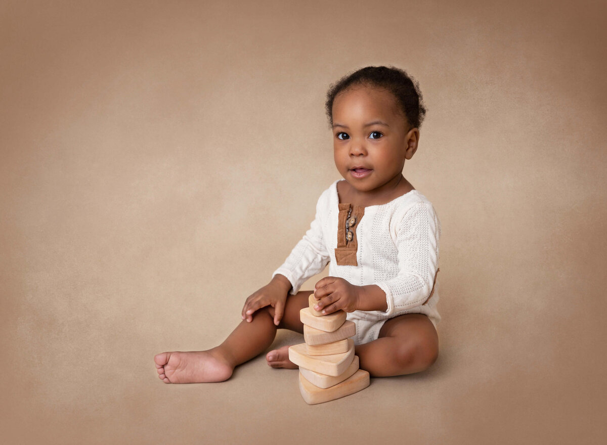 6-month-old baby boy playing with toys for his milestone photoshoot in New York City. NYC photography session celebrating baby milestones