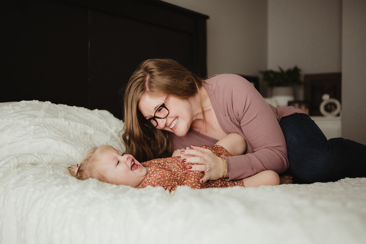mom and daughter playing on bed