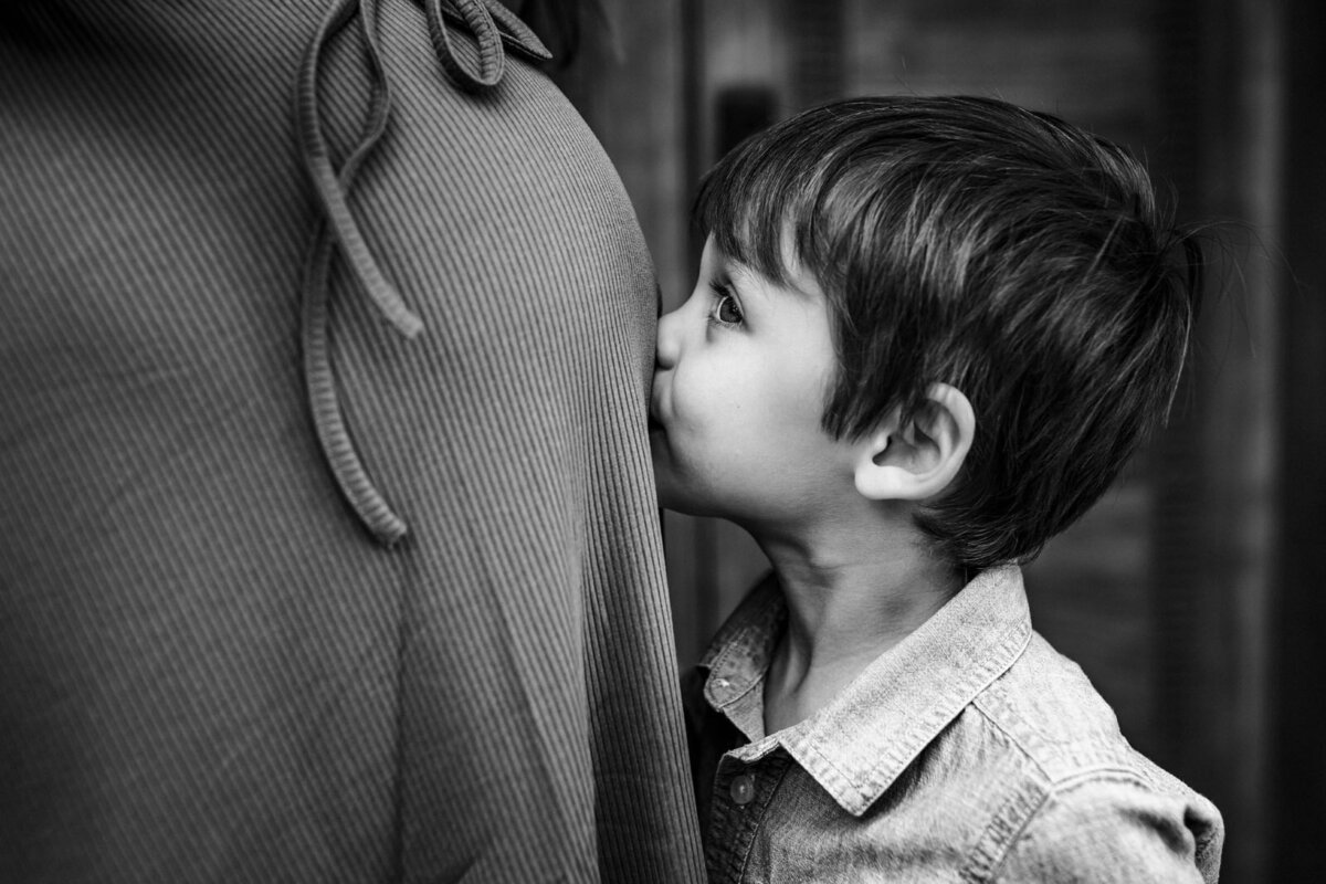 boy kissing his mom's baby bump at Berkeley park