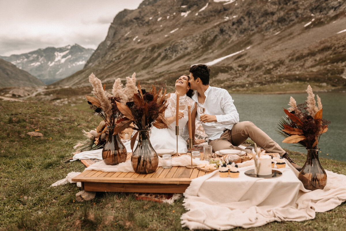 Brautpaar an einer gedeckten Tafel an einem Gebirgssee in den Schweizer Alpen