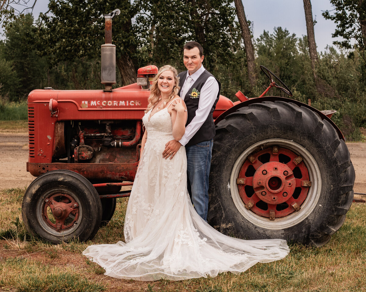 Bride and groom pose with a tractor
