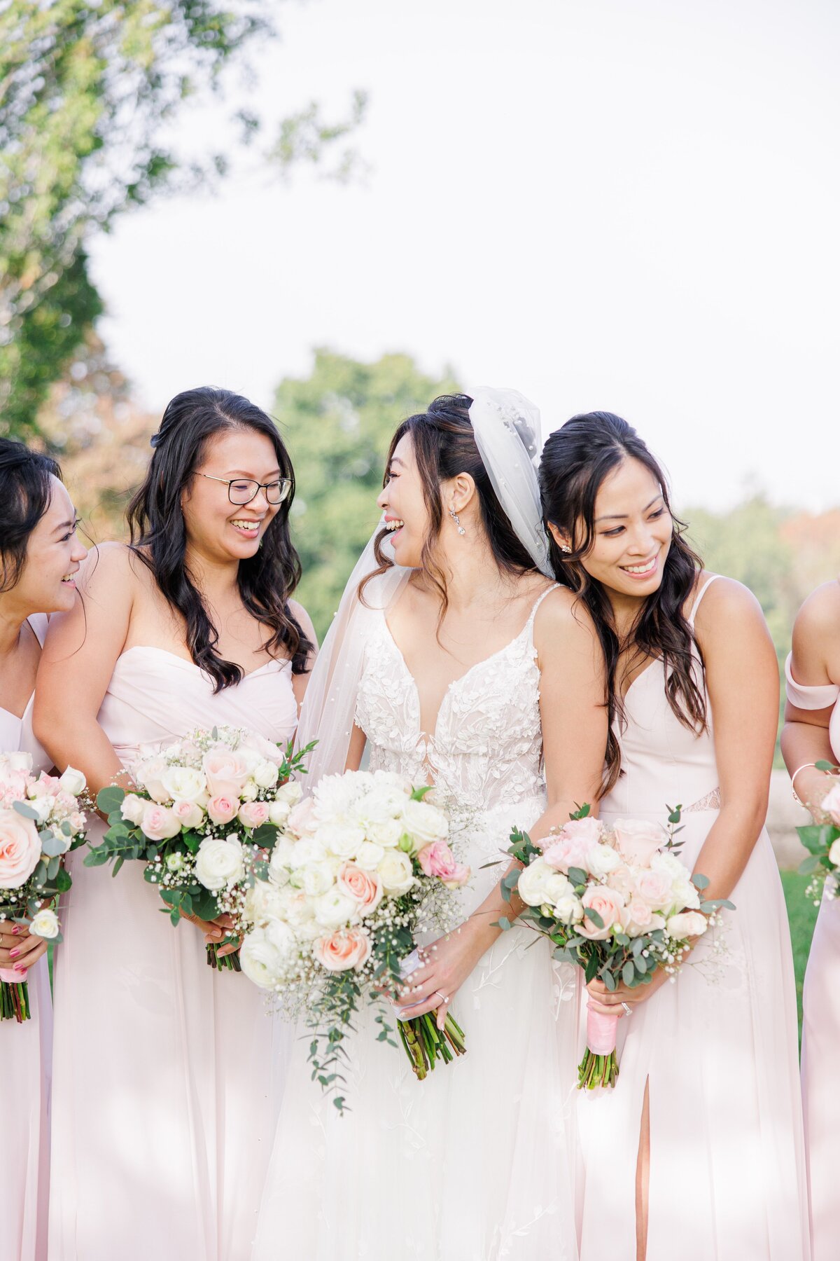 Bride smiling and laughing with her bridesmaids representing a Boston wedding photographer