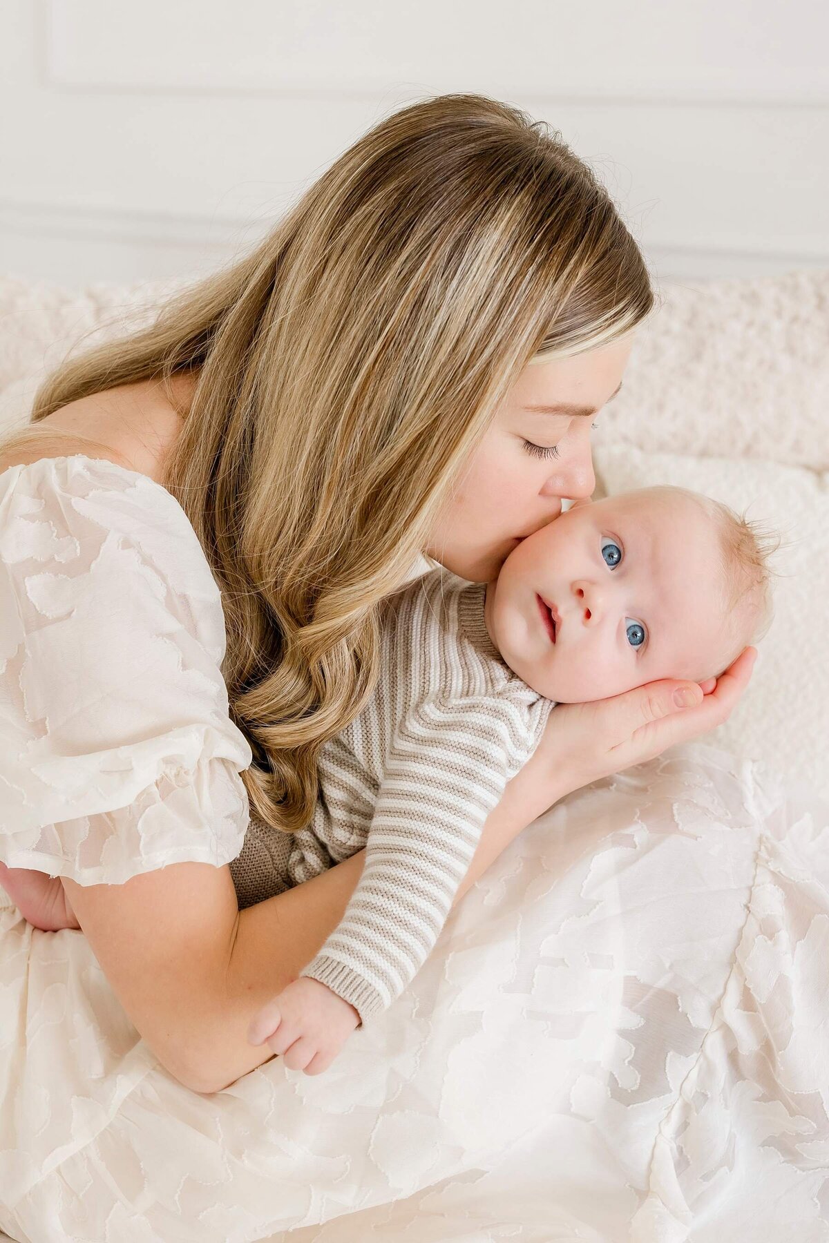 mom kisses newborn baby boy