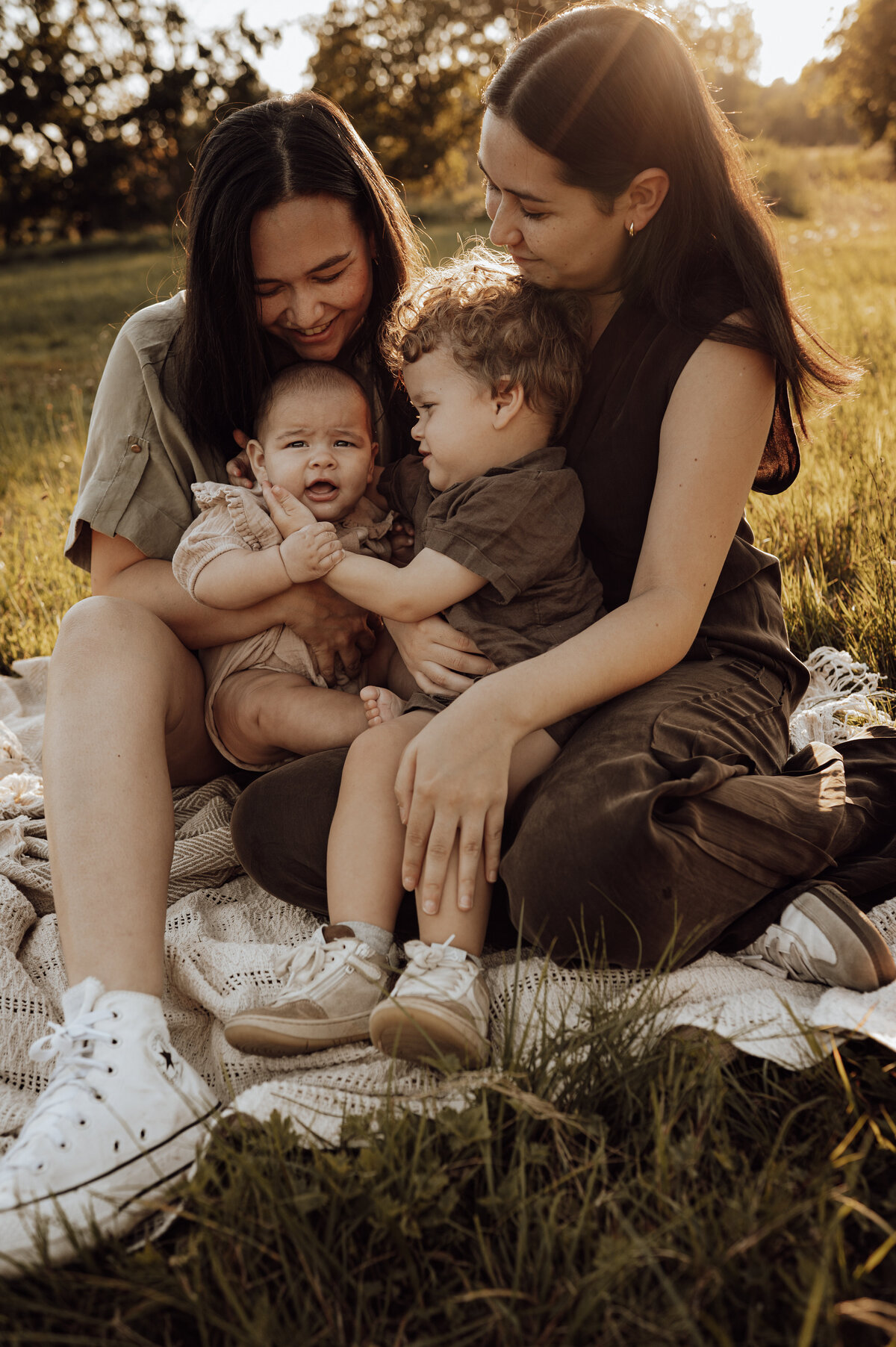 Twee vrouwen omhelzen hun kindjes tijdens gezinsshoot