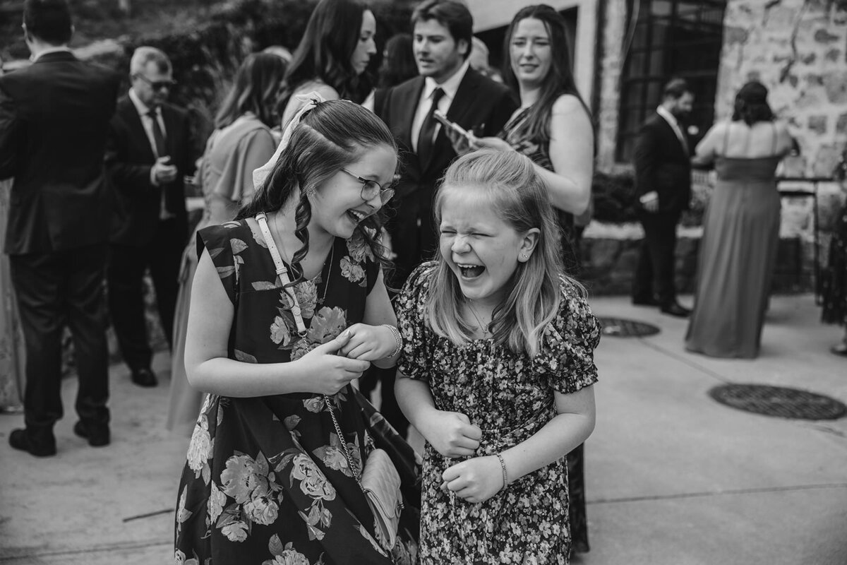 Two small kids laughing at a wedding reception 