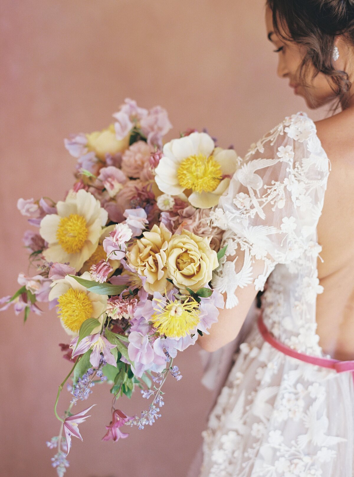 bride holding a bridal bouquet of purple pink and yellow flowers