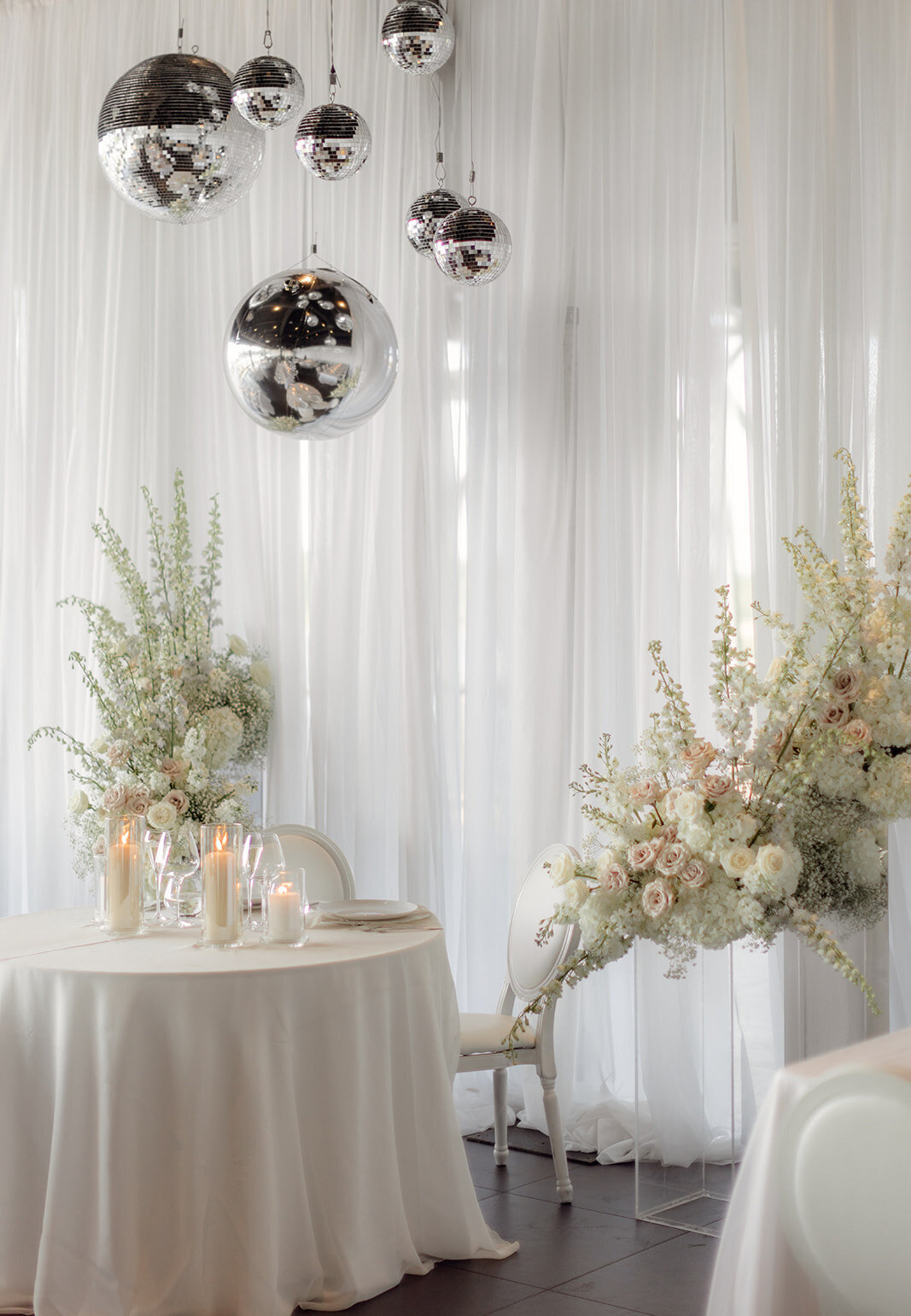 A table at a Science Centre wedding reception decorated with elegant white flowers and disco balls.