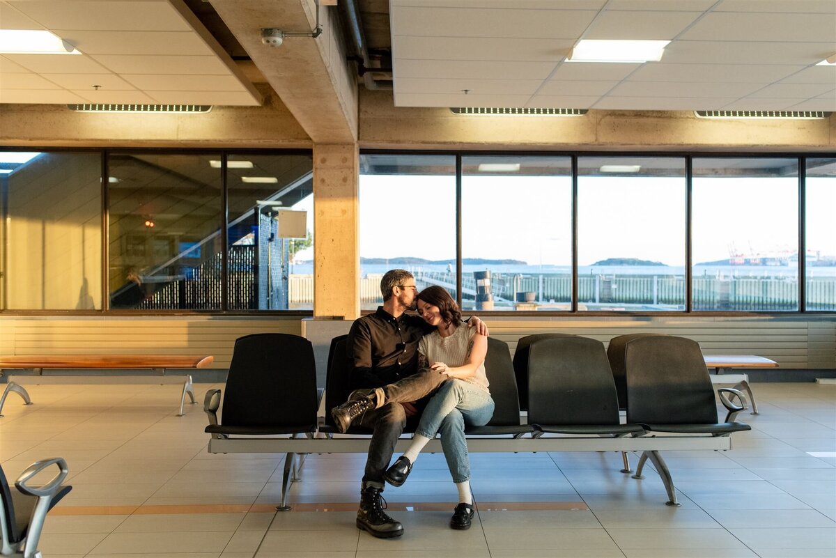 Couple sit on bench in Dartmouth ferry terminal during Halifax engagement session