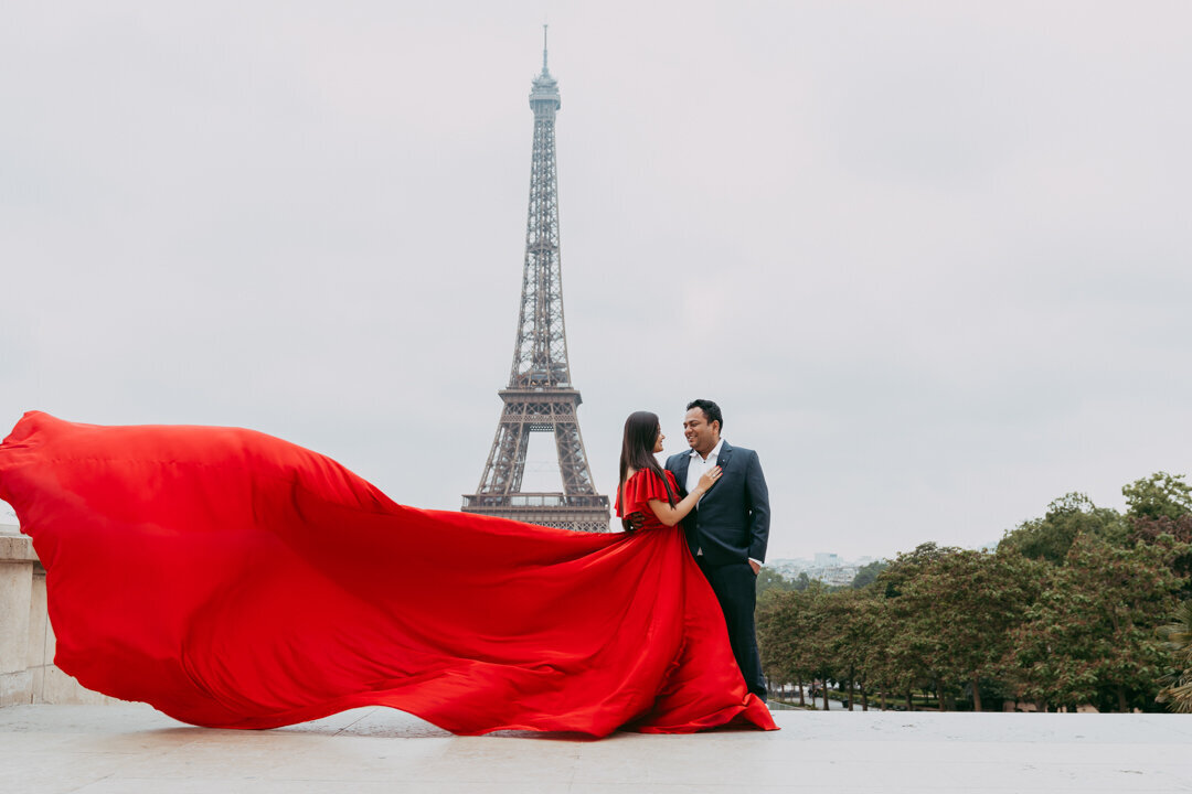 Trocadero couple photoshoot Paris, red flying dress, cloudy Eiffel Tower backdrop