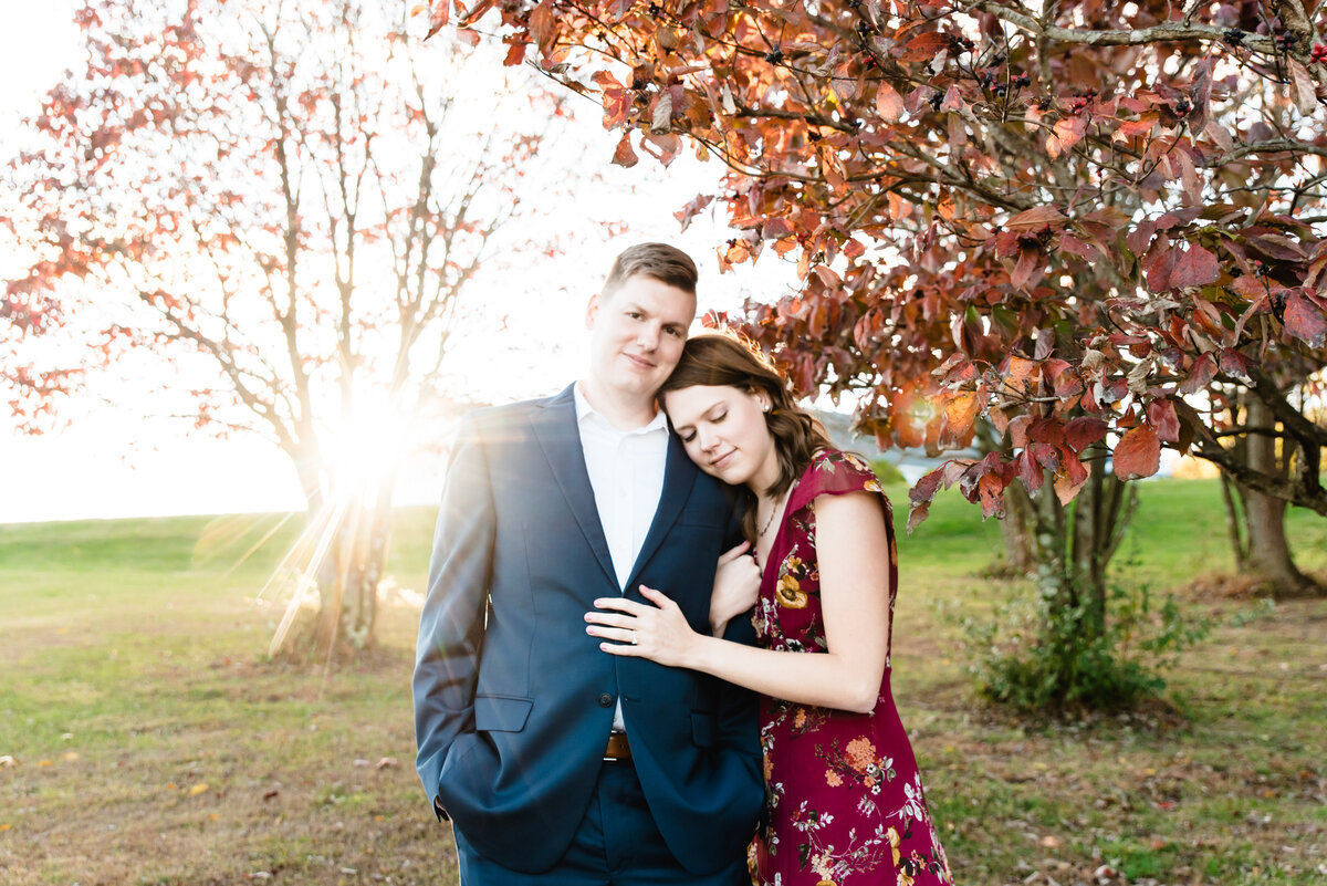 bride leans into groom and smiles with sun setting behind them and fall leaves in the background
