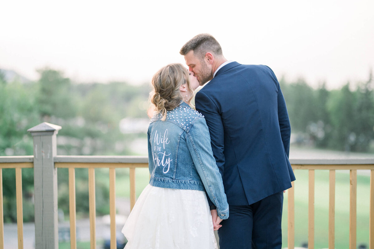 Bride and groom kissing with their backs to the Toronto wedding photographer to show special made jacket