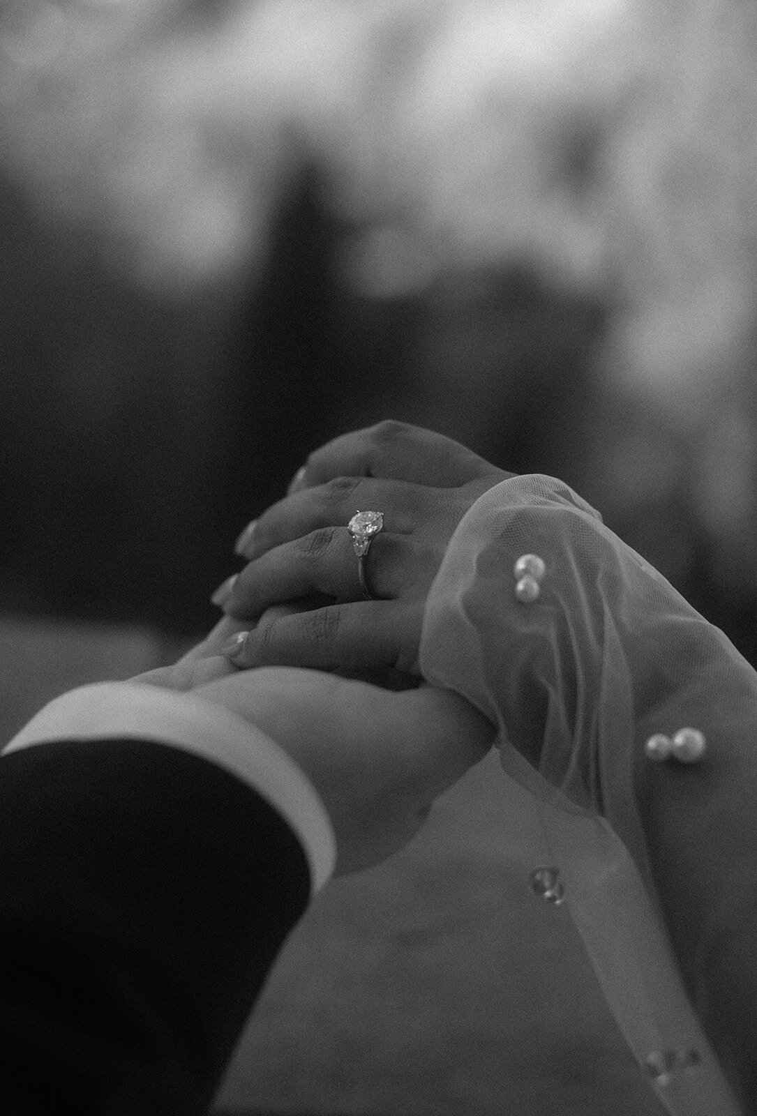 black and white photo of wedding ring and couple holding hands