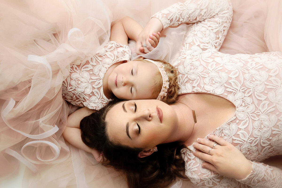 st-louis-motherhood-photographer-mother-and-daughter-lying-head-to-head-with-heads-together-wearing-matching-blush-lace-dresses