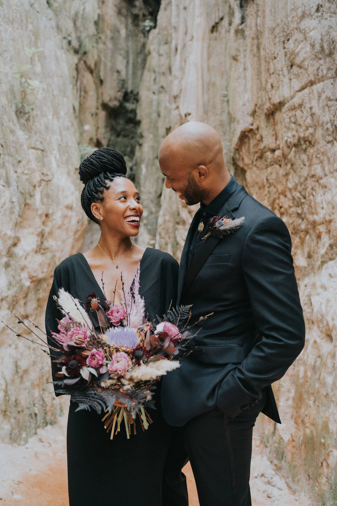 Black couple wearing black outfits holding pink bouquet