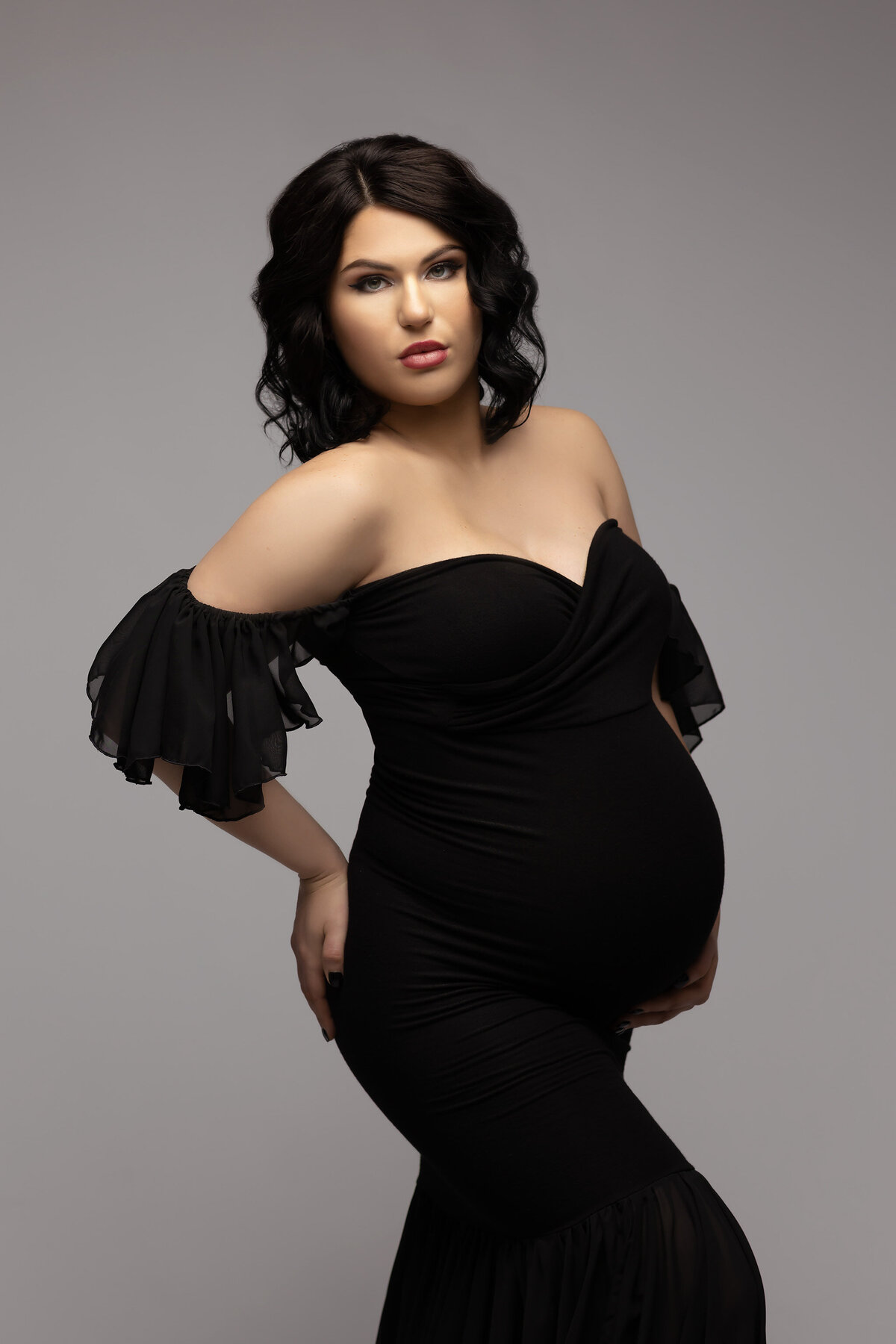Dallas maternity photographer captures woman in a chic black gown, exuding confidence and grace. Captured by Lindsay Walden Photography.
