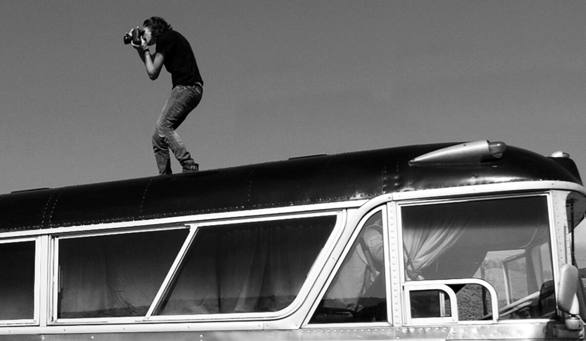 On Location black and white photo Mark Maryanovich Photography Ashcroft standing on top of tour bus while taking photos