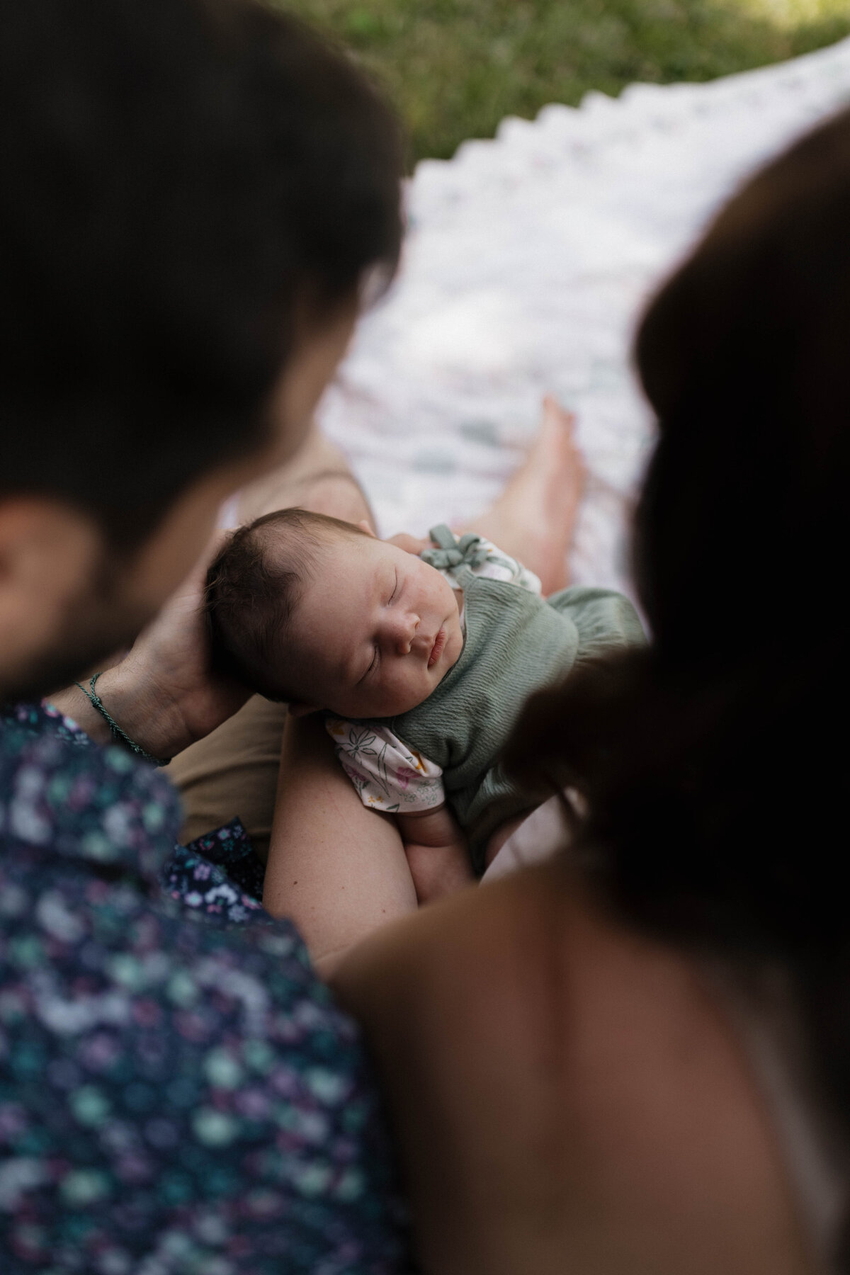 A softly lit image of a newborn peacefully sleeping while held by loving parents, captured in a documentary photography style.