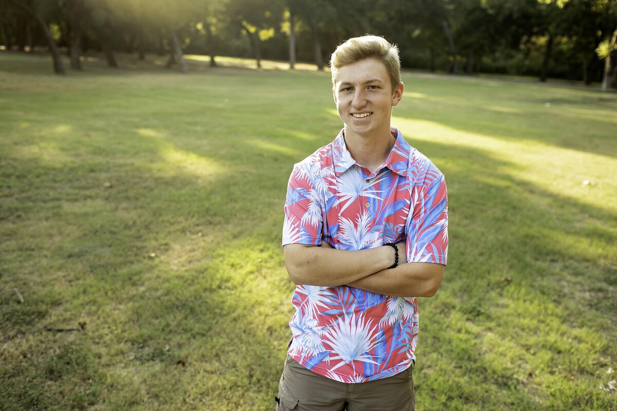 A high school senior stands with their arms crossed, exuding confidence and strength
