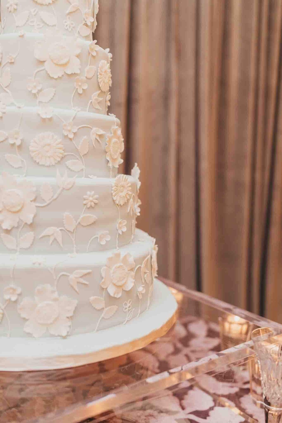 floral fondant on wedding cake sitting on acrylic cake stand.