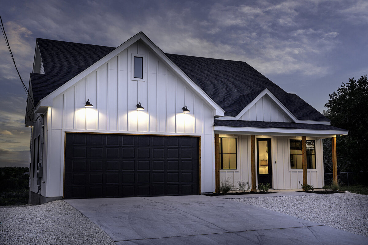 white board and batten house with black windows, wood columns and gooseneck barn lights