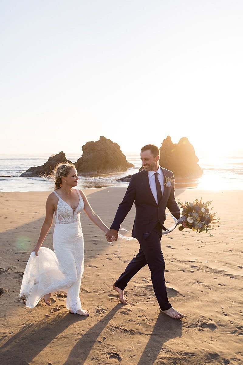 Adventurous newlyweds walking on Oregon beach at sunset