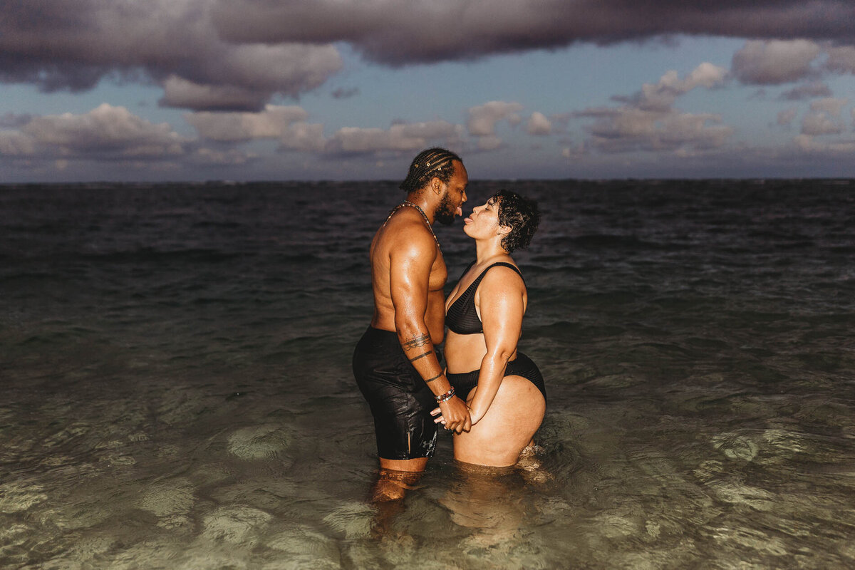 Couple standing in the ocean at night laughing and embracing — romantic Oahu couples beach photography by Leslie Carbajal.