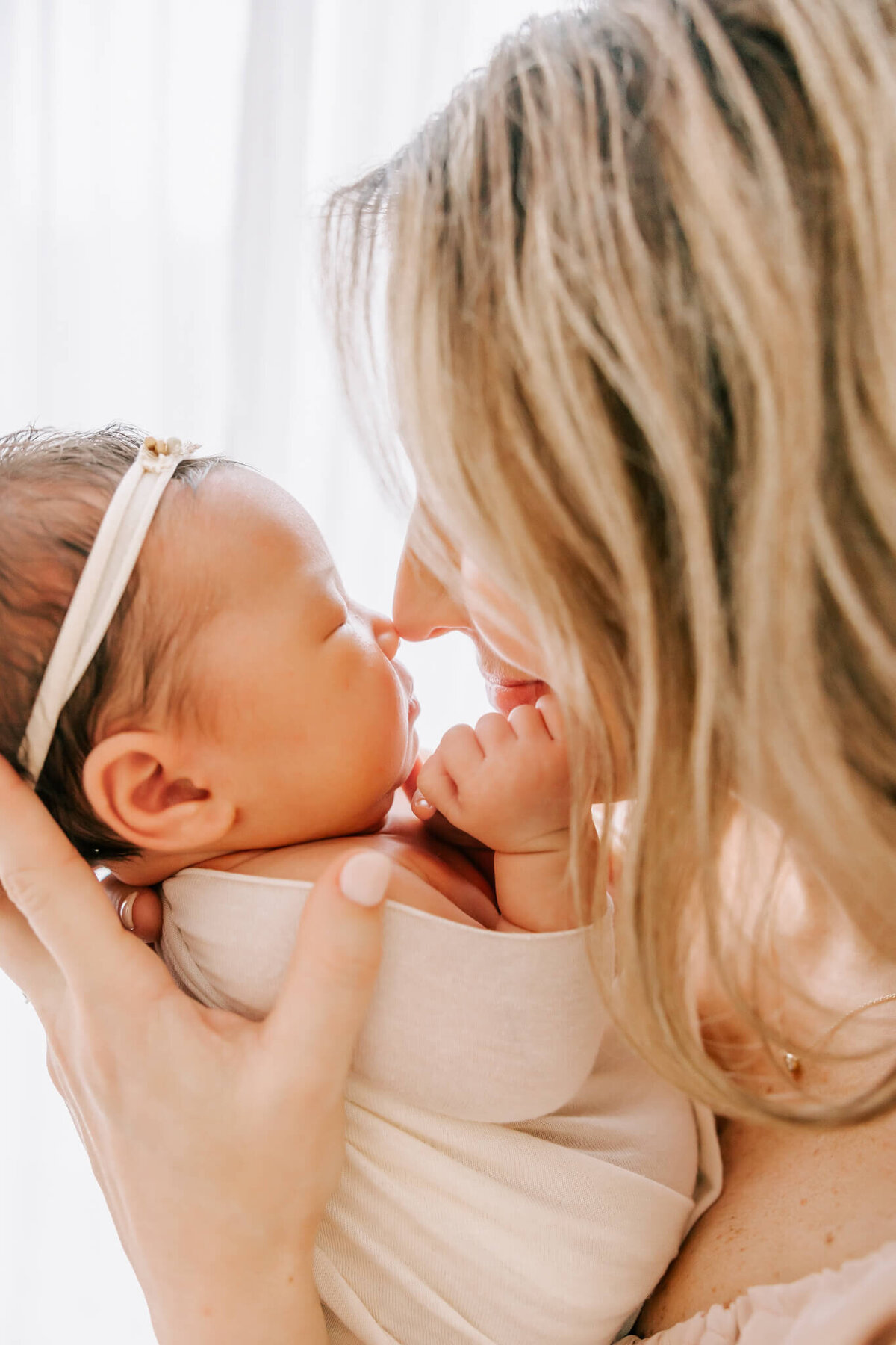 portrait of a mom and daughter touching faces in their newborn portrait session