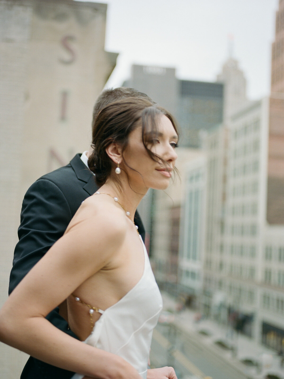 wind blows bride's hair as she leans over balcony of Detroit hotel