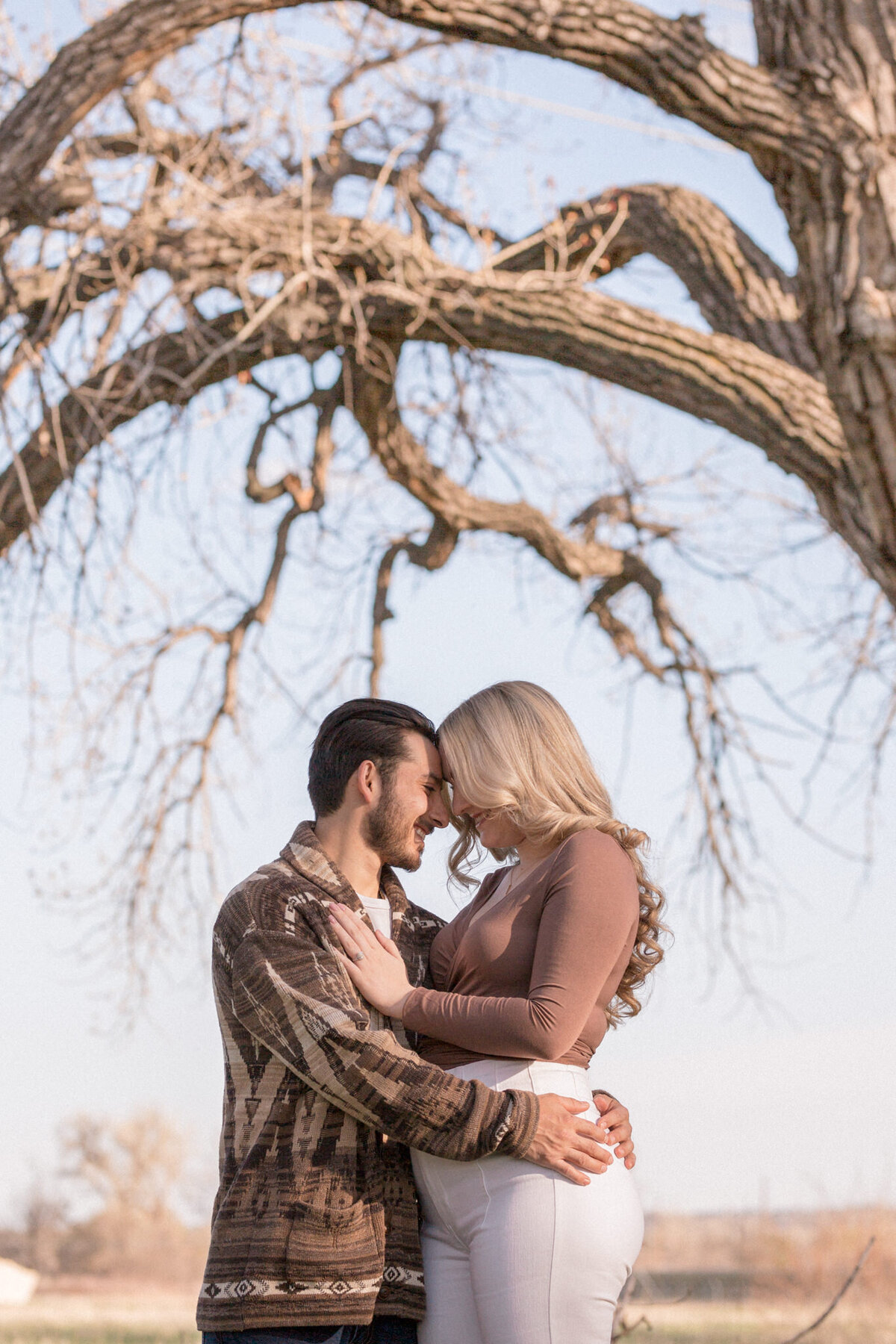 A man wraps his arms around his fiancée as she shows off her new engagement ring