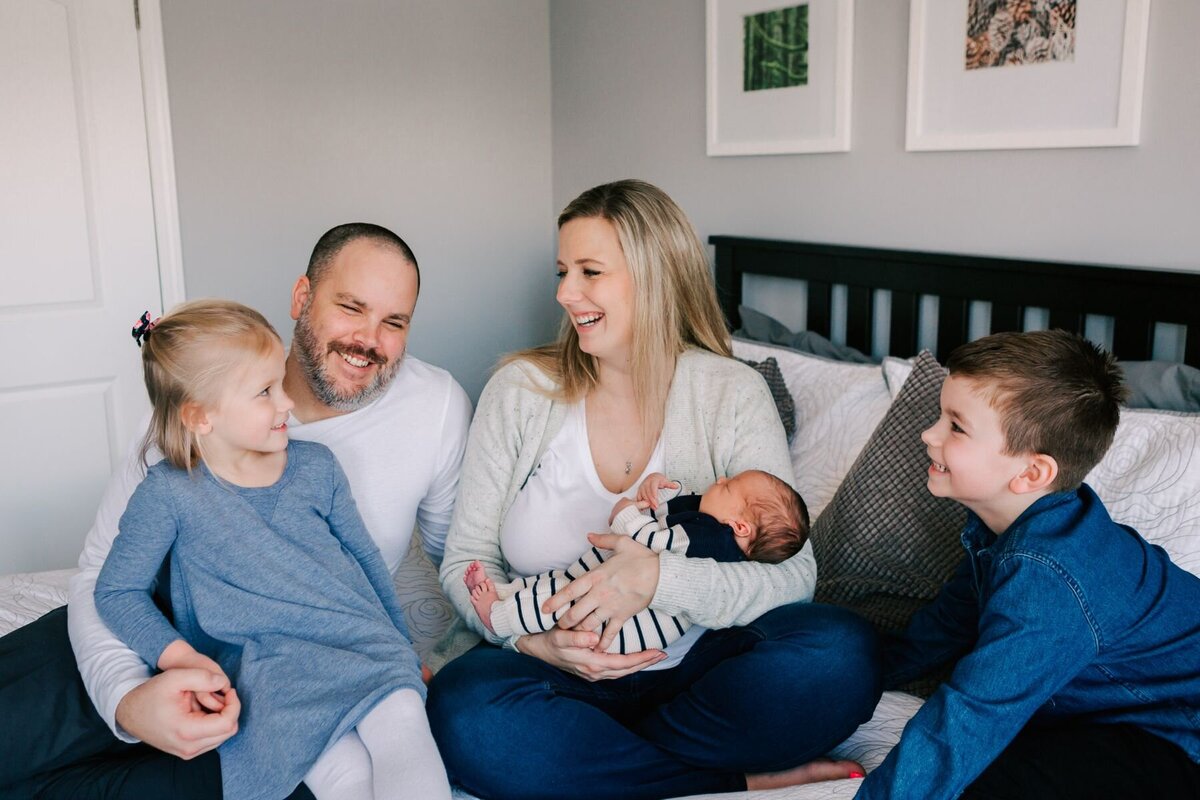 family laughs and smiles at the eldest daughter during a newborn session