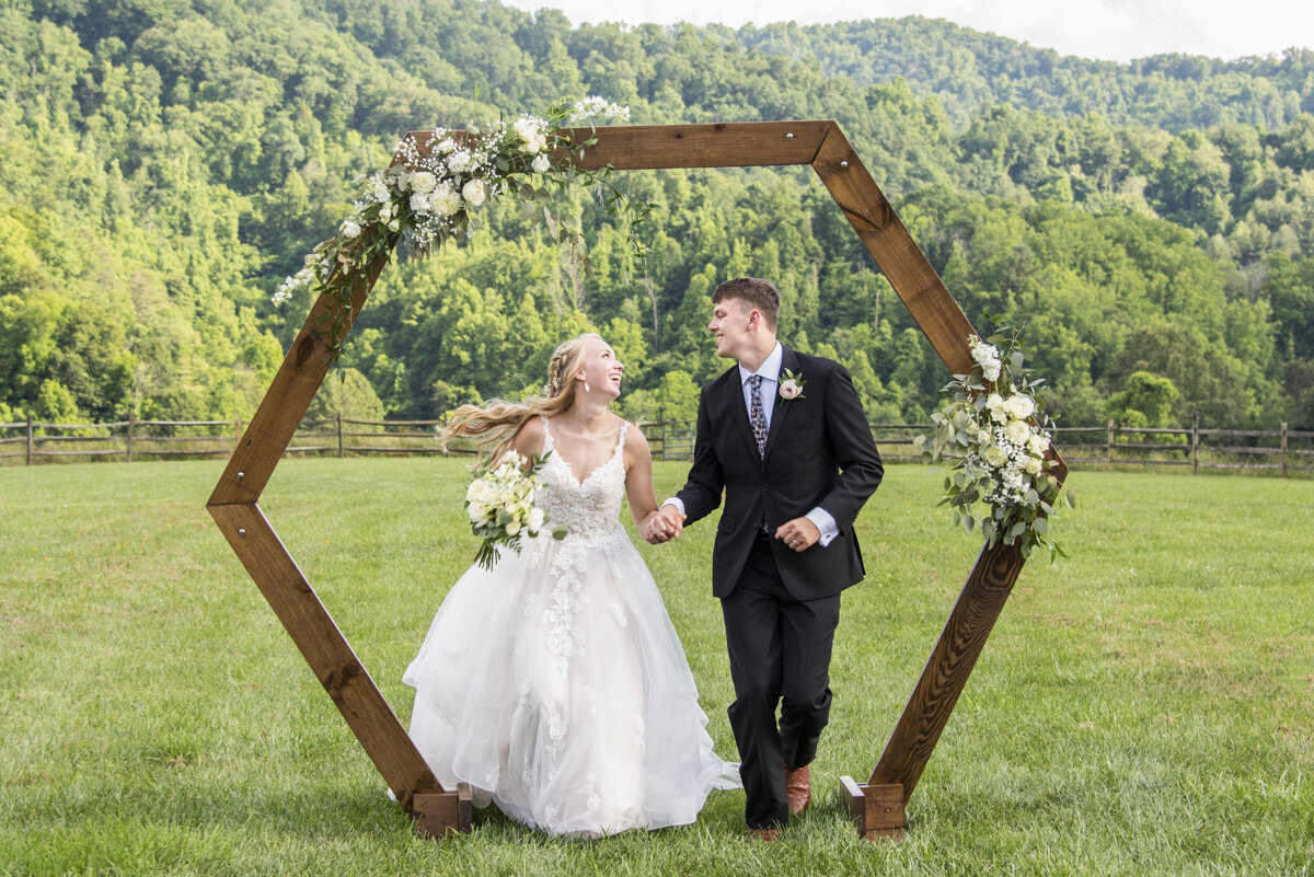 Couple running under arbor at Claxton Farm wedding