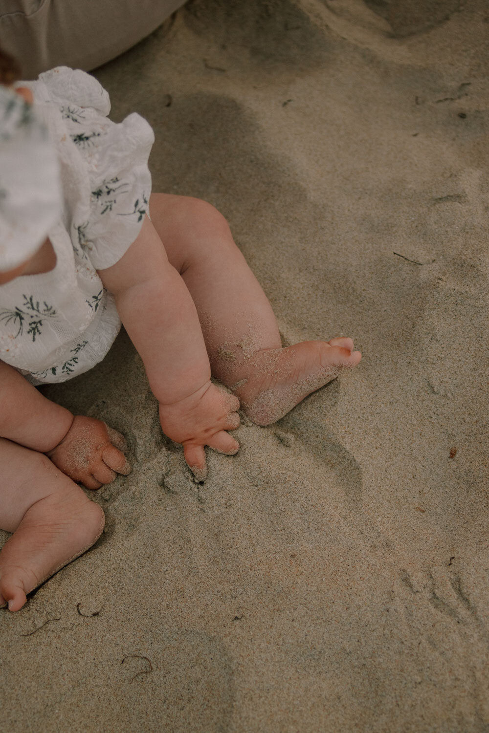Baby’s feet and hands touching the sand
