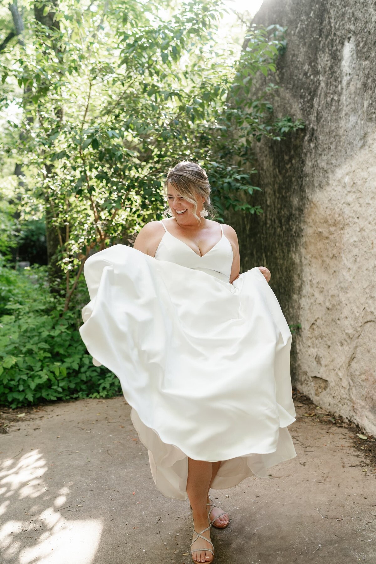 Bride twirling in her dress at elopement in front of stone wall in Austin, Texas