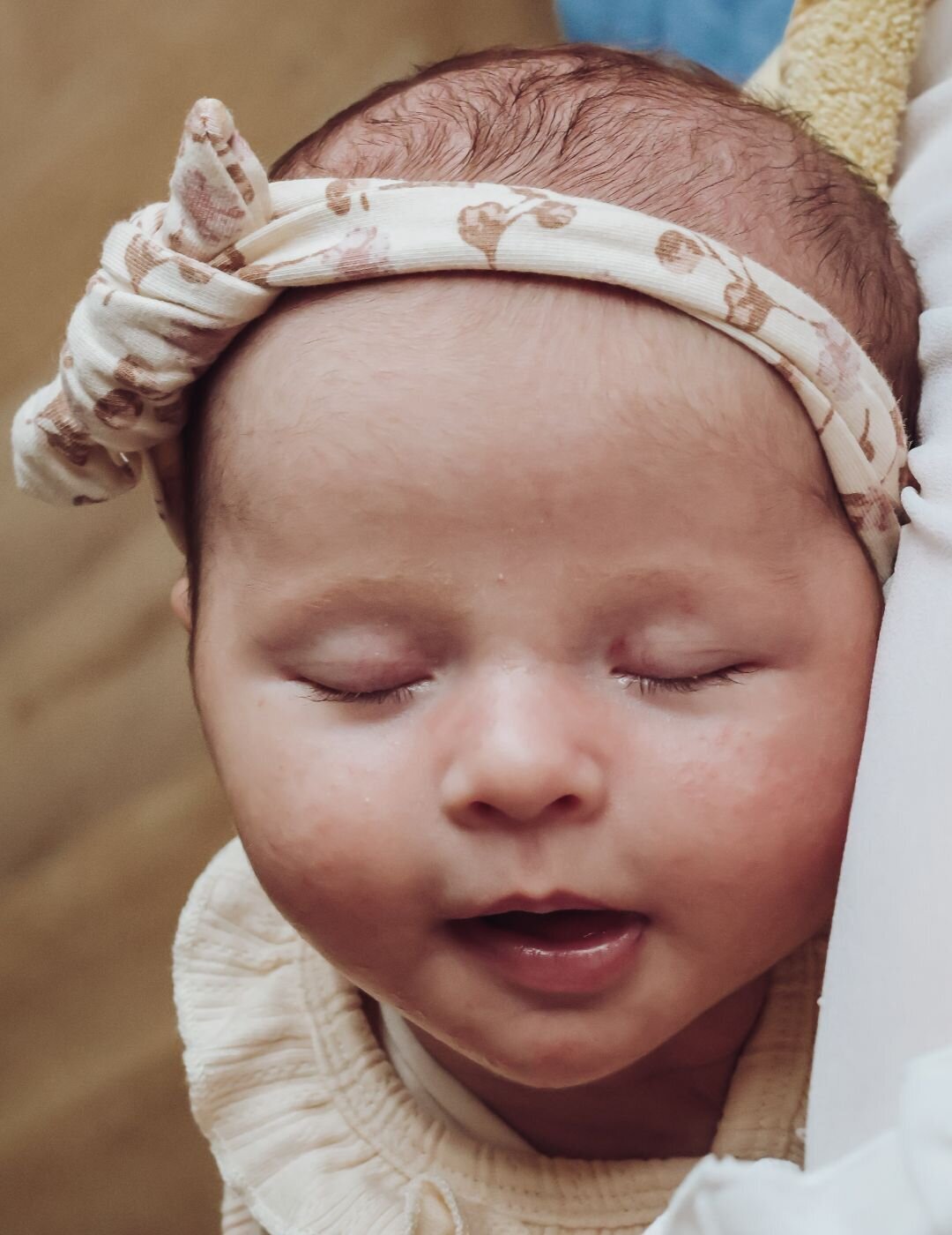 Het lieve gezicht van een pasgeboren baby met een glimlach, liggend op een zachte ondergrond