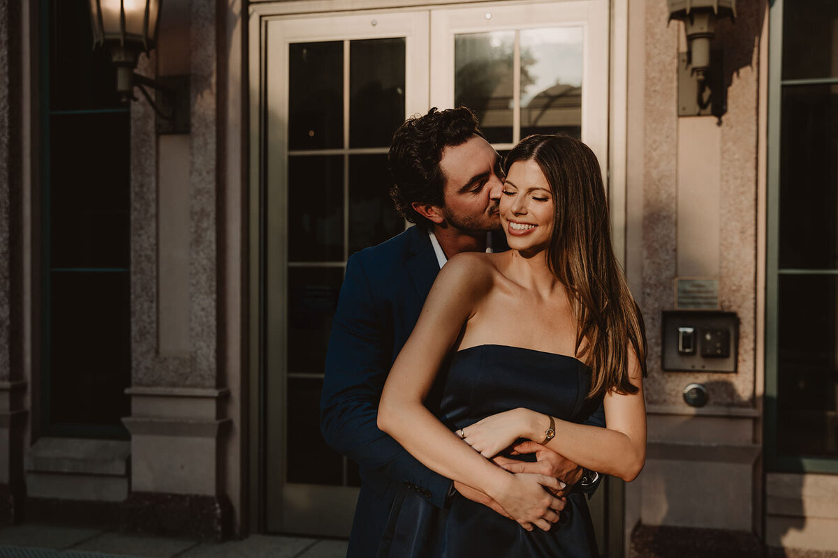 A person hugging their partner from behind and kissing their cheek 